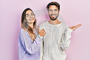 Young hispanic couple wearing casual clothes showing palm hand and doing ok gesture with thumbs up, smiling happy and cheerful