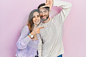 Young hispanic couple wearing casual clothes smiling making frame with hands and fingers with happy face