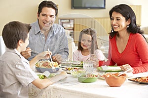 Young Hispanic Family Enjoying Meal At Home