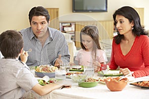 Young Hispanic Family Enjoying Meal At Home