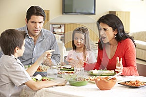 Young Hispanic Family Enjoying Meal At Home