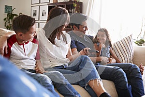 Young Hispanic family sitting on the sofa at home to watch TV, looking at each other, close up