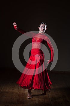 Young hispanic flamenco dancer in red dress isolated on black background