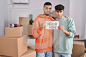 Young hispanic gay couple moving to a new home clueless and confused expression