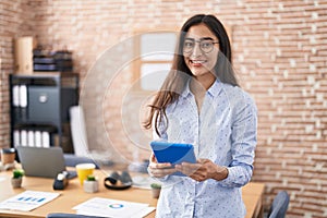 Young hispanic girl business worker smiling confident using touchpad at office