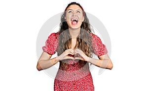 Young hispanic girl doing heart symbol with hands angry and mad screaming frustrated and furious, shouting with anger looking up