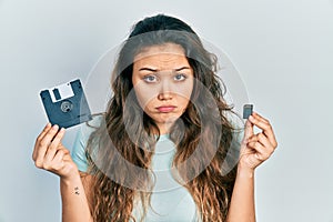 Young hispanic girl holding floppy disk and sdxc card depressed and worry for distress, crying angry and afraid