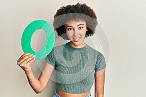 Young hispanic girl holding number zero looking positive and happy standing and smiling with a confident smile showing teeth