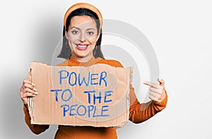 Young hispanic girl holding power to the people banner smiling happy pointing with hand and finger