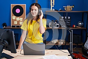 Young hispanic girl listening to music wearing headphones looking positive and happy standing and smiling with a confident smile