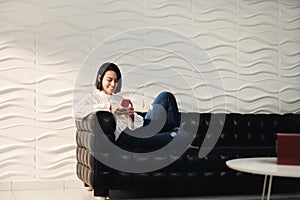 Young Hispanic Girl Messaging With Cell Phone On Sofa