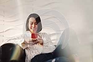 Young Hispanic Girl Messaging With Cell Phone On Sofa