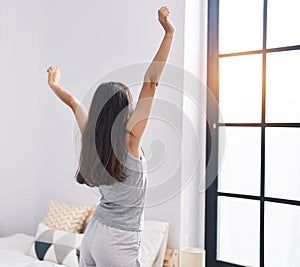 Young hispanic girl smiling confident stretching arms at bedroom