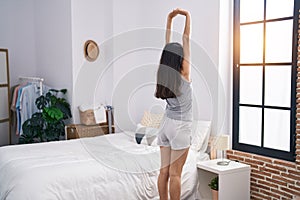 Young hispanic girl smiling confident stretching arms at bedroom