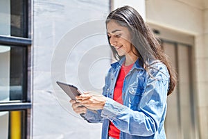 Young hispanic girl smiling confident using touchpad at street