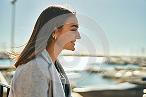 Young hispanic girl smiling happy looking to the horizon at the city