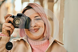 Young hispanic girl smiling happy using reflex camera at the city