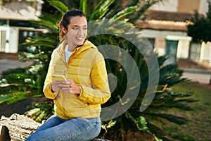 Young hispanic girl smiling happy using smartphone at the park