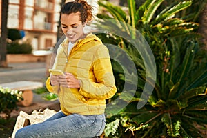 Young hispanic girl smiling happy using smartphone at the park