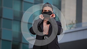 Young hispanic girl standing on city building background looking at camera businesswoman wearing medical protective mask