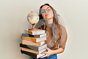 Young hispanic girl studying geography looking at the camera blowing a kiss being lovely and sexy