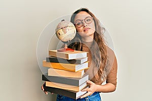 Young hispanic girl studying geography relaxed with serious expression on face