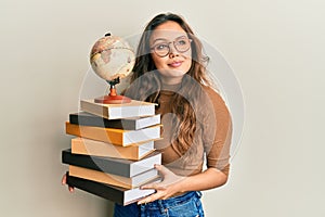 Young hispanic girl studying geography smiling looking to the side and staring away thinking