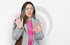Young hispanic girl wearing business clothes afraid and terrified with fear expression stop gesture with hands, shouting in shock