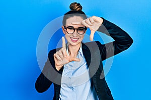 Young hispanic girl wearing business clothes and glasses smiling making frame with hands and fingers with happy face