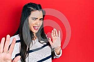 Young hispanic girl wearing casual clothes afraid and terrified with fear expression stop gesture with hands, shouting in shock