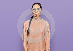 Young hispanic girl wearing casual clothes and glasses afraid and shocked with surprise expression, fear and excited face