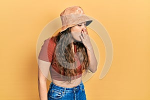 Young hispanic girl wearing casual clothes and hat bored yawning tired covering mouth with hand