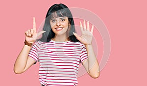 Young hispanic girl wearing casual clothes showing and pointing up with fingers number seven while smiling confident and happy