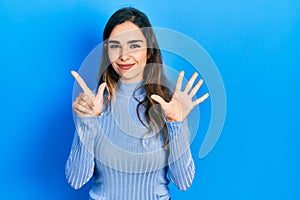 Young hispanic girl wearing casual clothes showing and pointing up with fingers number seven while smiling confident and happy