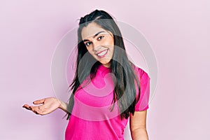 Young hispanic girl wearing casual pink t shirt smiling cheerful with open arms as friendly welcome, positive and confident