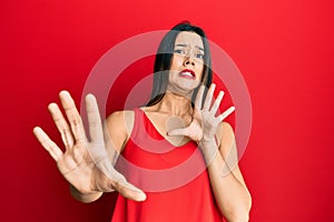 Young hispanic girl wearing casual style with sleeveless shirt afraid and terrified with fear expression stop gesture with hands,