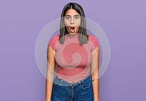 Young hispanic girl wearing casual t shirt afraid and shocked with surprise expression, fear and excited face