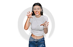 Young hispanic girl wearing casual white t shirt smiling funny doing claw gesture as cat, aggressive and sexy expression