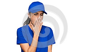 Young hispanic girl wearing delivery courier uniform bored yawning tired covering mouth with hand