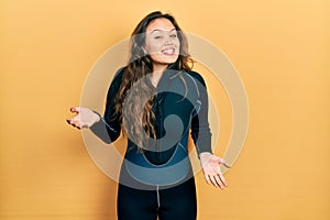 Young hispanic girl wearing diver neoprene uniform smiling cheerful with open arms as friendly welcome, positive and confident