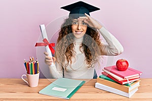 Young hispanic girl wearing graduated hat holding diploma stressed and frustrated with hand on head, surprised and angry face