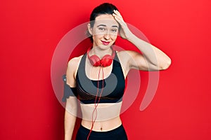 Young hispanic girl wearing gym clothes and using headphones confuse and wonder about question