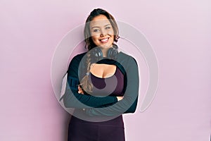 Young hispanic girl wearing sportswear and headphones happy face smiling with crossed arms looking at the camera