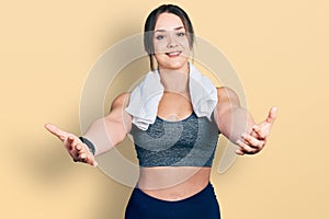 Young hispanic girl wearing sportswear and towel looking at the camera smiling with open arms for hug