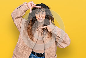 Young hispanic girl wearing winter clothes smiling making frame with hands and fingers with happy face