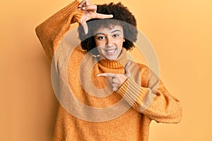 Young hispanic girl wearing wool winter sweater smiling making frame with hands and fingers with happy face