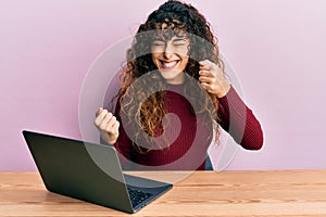 Young hispanic girl working using computer laptop celebrating surprised and amazed for success with arms raised and eyes closed