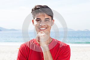 Young hispanic guy at beach looking at camera