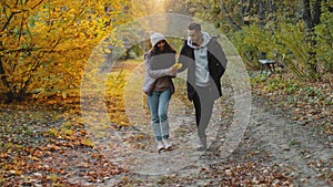 Young hispanic happy couple in love walking outdoors going in autumn woods in sunshine enjoying nature chatting smiling