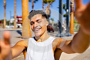 Young hispanic man 20- 25 years old smiling happy looking to the camera outdoors taking selfie on smartphone camera at